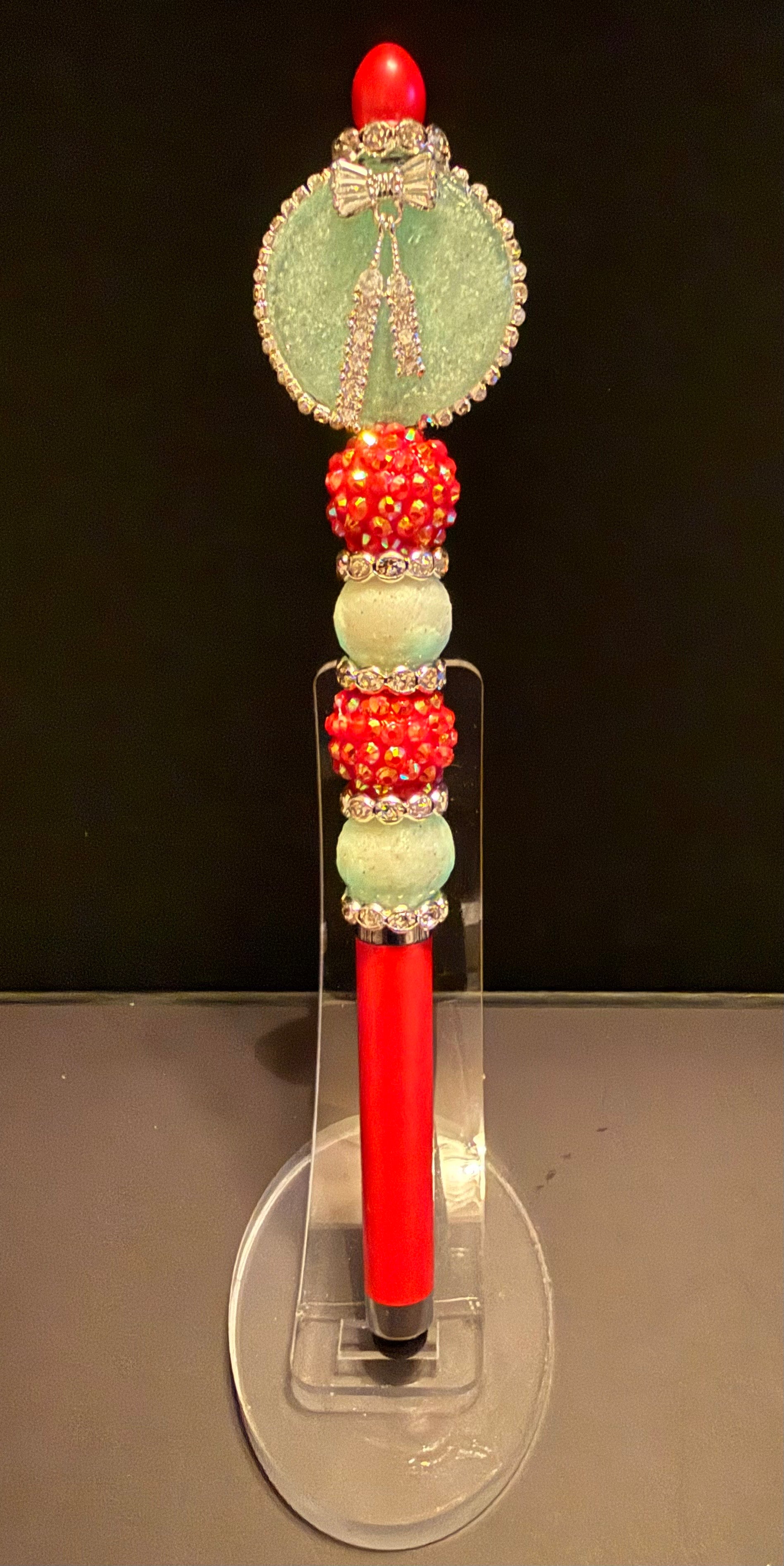 This red beaded stylus into a pen does glow in the dark and  has a silver bow charm